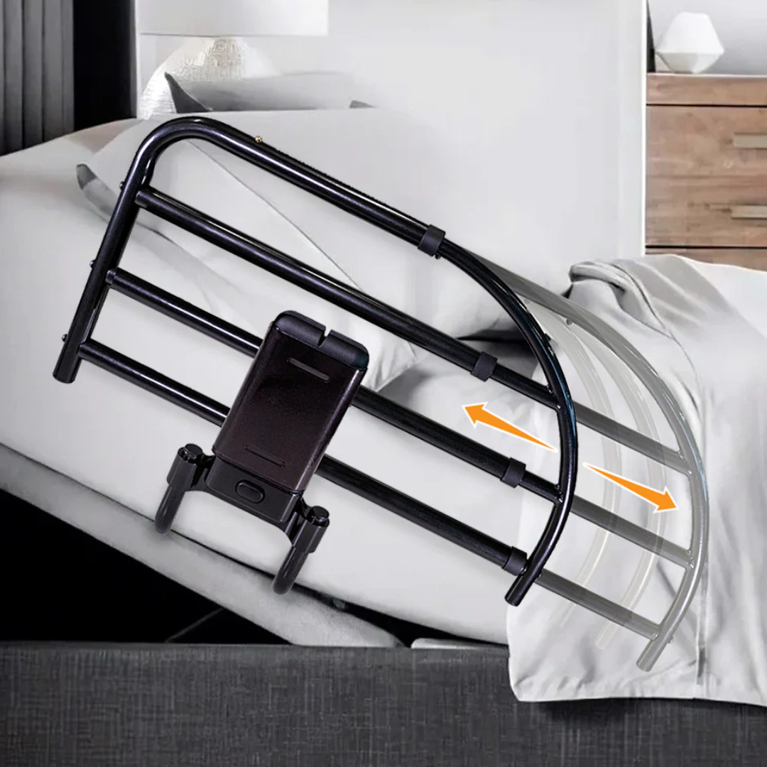 The Stander Click-N-Go Extendable Bed Rail for Adjustable Beds attaches to beds with white sheets, providing nighttime safety. Two orange arrows show its extendable feature, with a nightstand and lamp in the background.